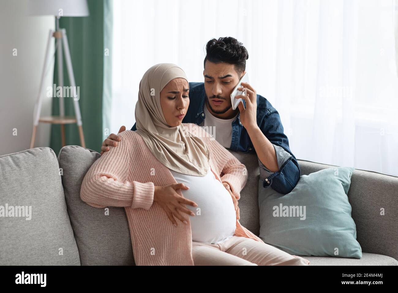Sorge Muslimischer Ehemann Ruft Notfall, Während Seine Schwangere Frau Zu Haben Kontraktionen Stockfoto