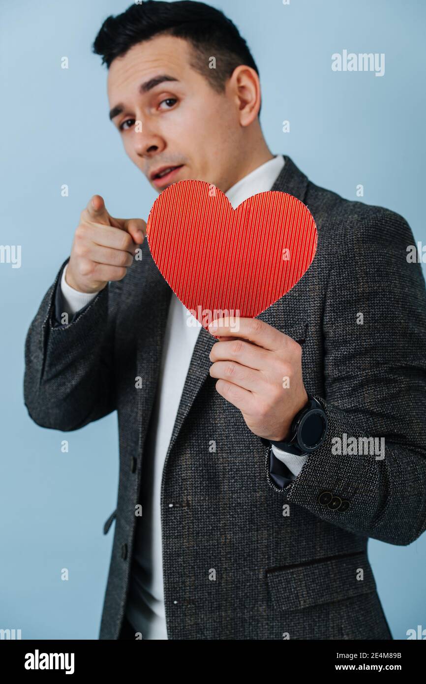 Der Kerl hält den valentine und zeigt seinen Finger nach vorne Stockfoto