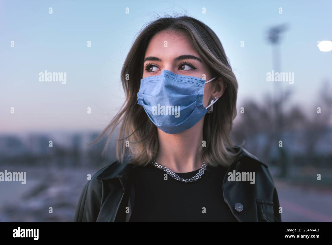 Porträt eines Teenagers Mädchen mit einer medizinischen Gesichtsmaske auf der Straße. Stockfoto