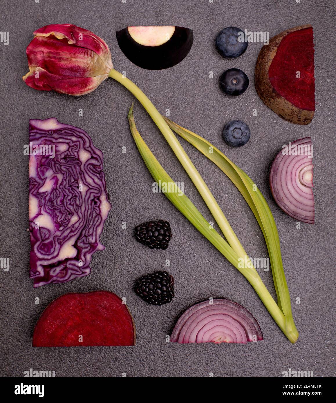 Tulpe, Eierpflanze, Heidelbeere, Rübenwurzel, rote Zwiebel Muster auf schwarzem Tisch. Geometrische flache Lage lila Pflanzen Konzept Stockfoto