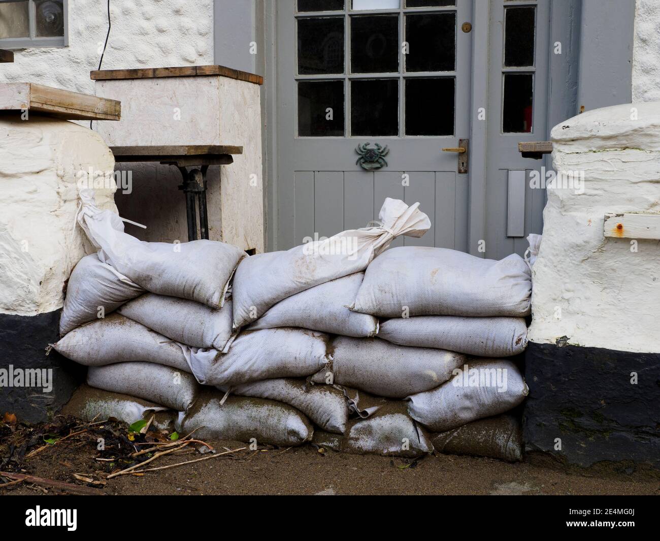 Sandsäcke schützen den Eingang zum Mote Restaurant, Port Isaac, Cornwall, Großbritannien Stockfoto