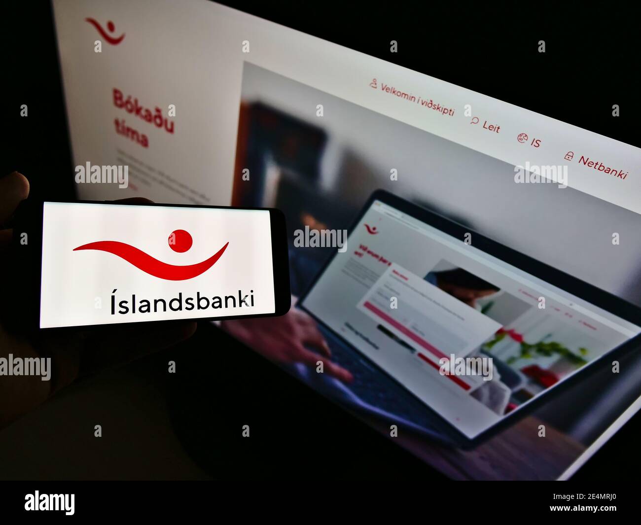 High-Angle-Ansicht der Person hält Smartphone mit Firmenlogo der isländischen Bank Íslandsbanki auf dem Bildschirm. Konzentrieren Sie sich auf die Anzeige von Mobiltelefonen. Stockfoto