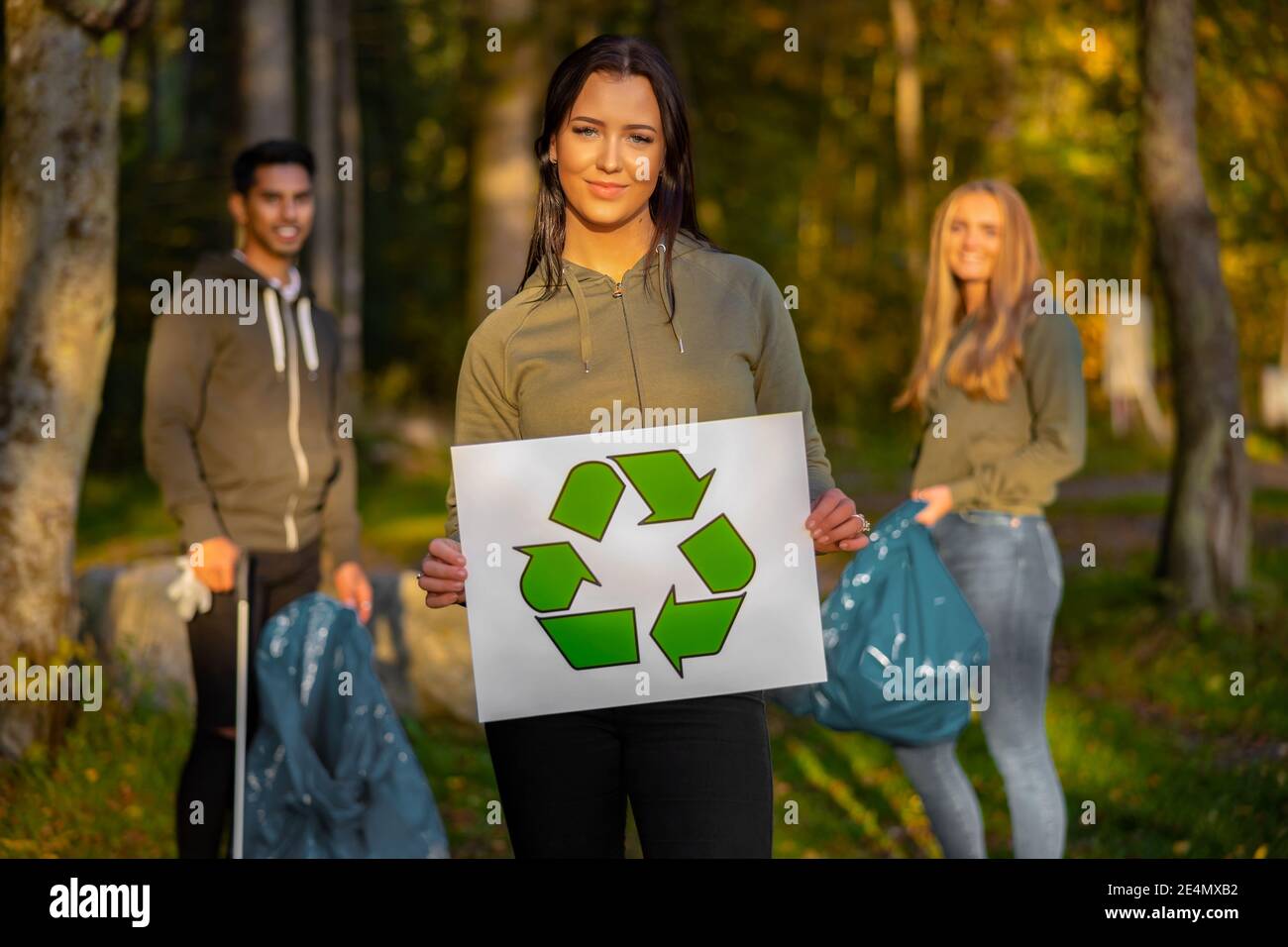 Selbstbewusste freiwillige Frau, die mit einem Symbol für das Recycling aufhält Stockfoto