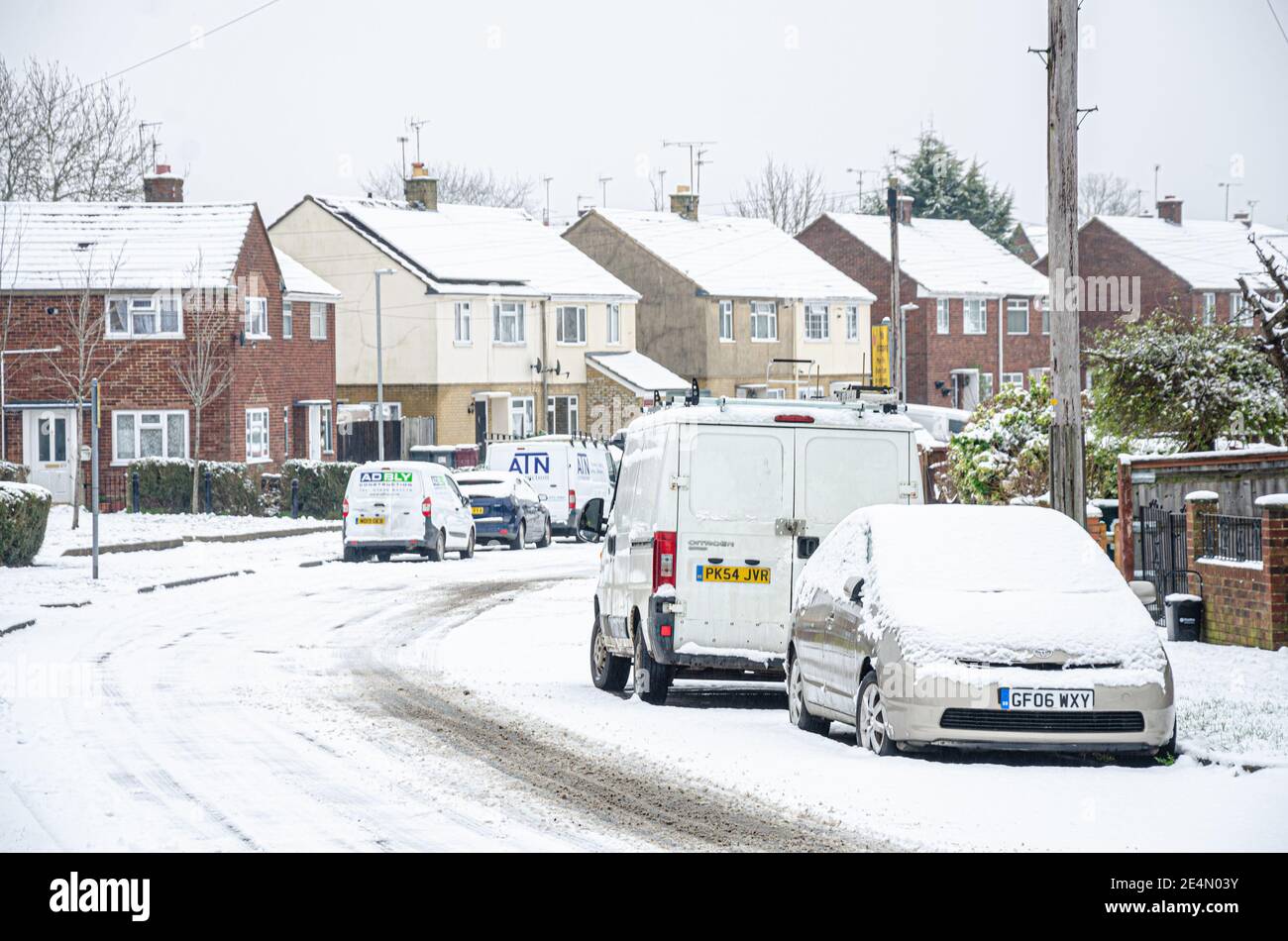 Eine Wohnstraße in Reading, Berkshire, Großbritannien ist mit Schnee bedeckt. Autospuren führen in die Ferne. Stockfoto