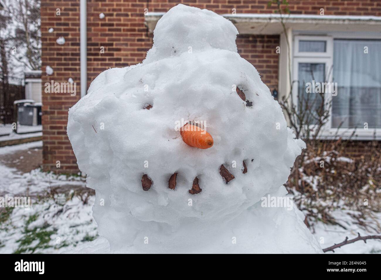 Der Kopf eines Schneemanns mit einer Karotte für eine Nase und Kieselsteinen für Augen und Mund. Stockfoto