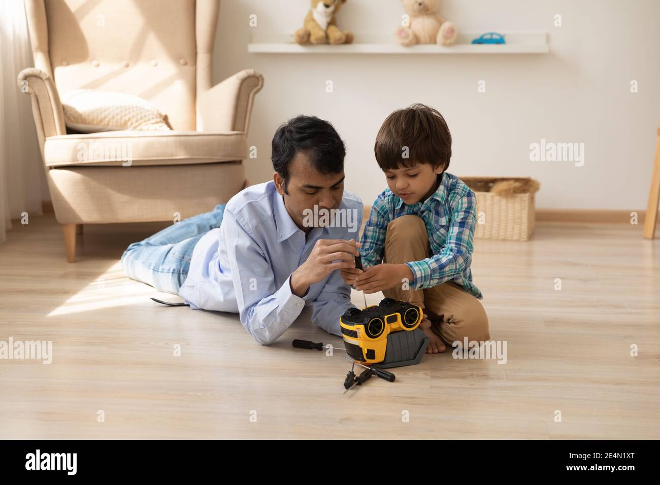 Caring hindu Papa helfen kleinen Sohn Kunststoff-LKW zu reparieren Stockfoto