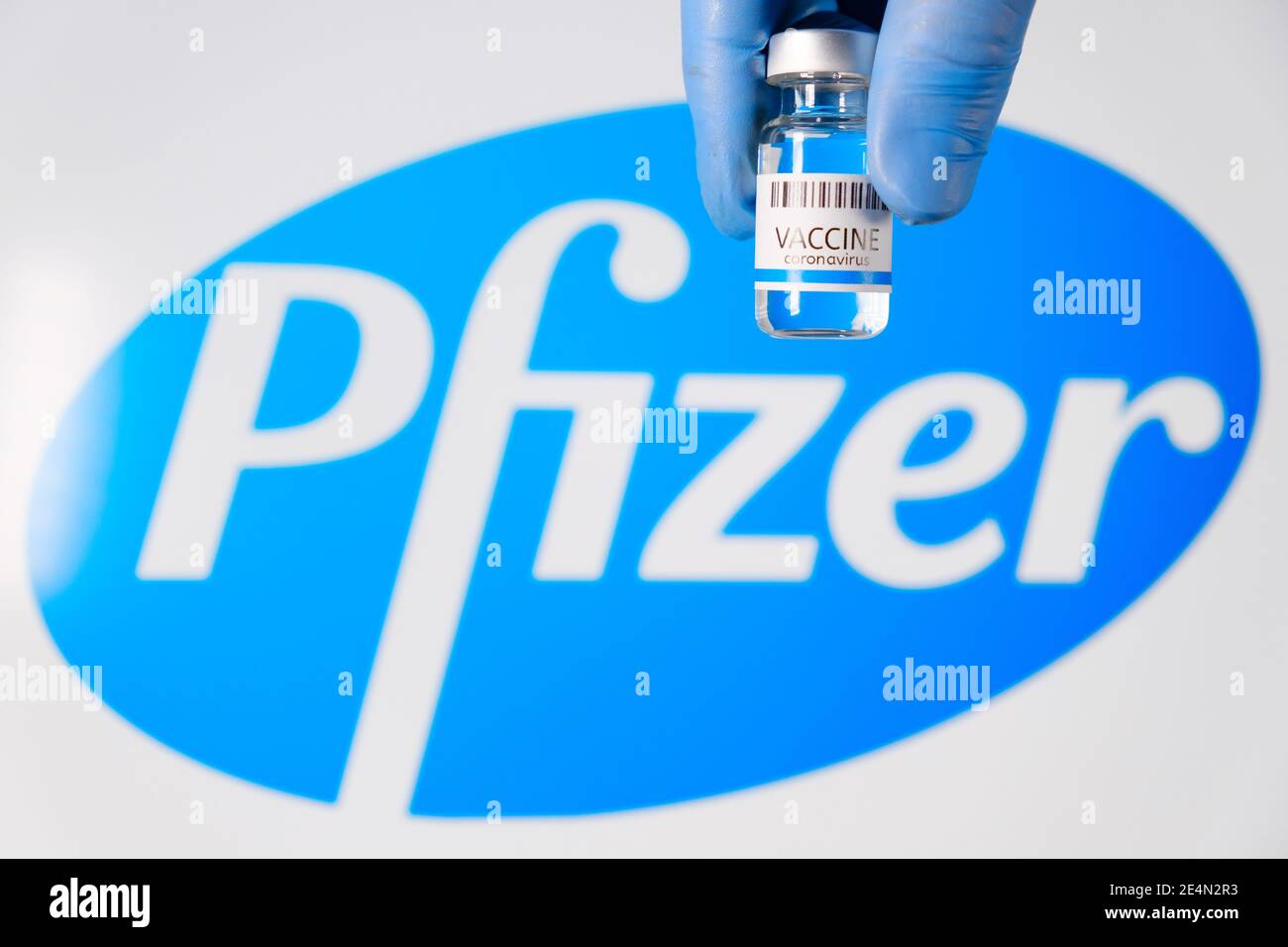 Pfizer-Impfstoff in der Flasche in der Hand der Ärzte in Gummihandschuhe auf dem Hintergrund des Logos, Januar 2021, San Francisco, USA Stockfoto