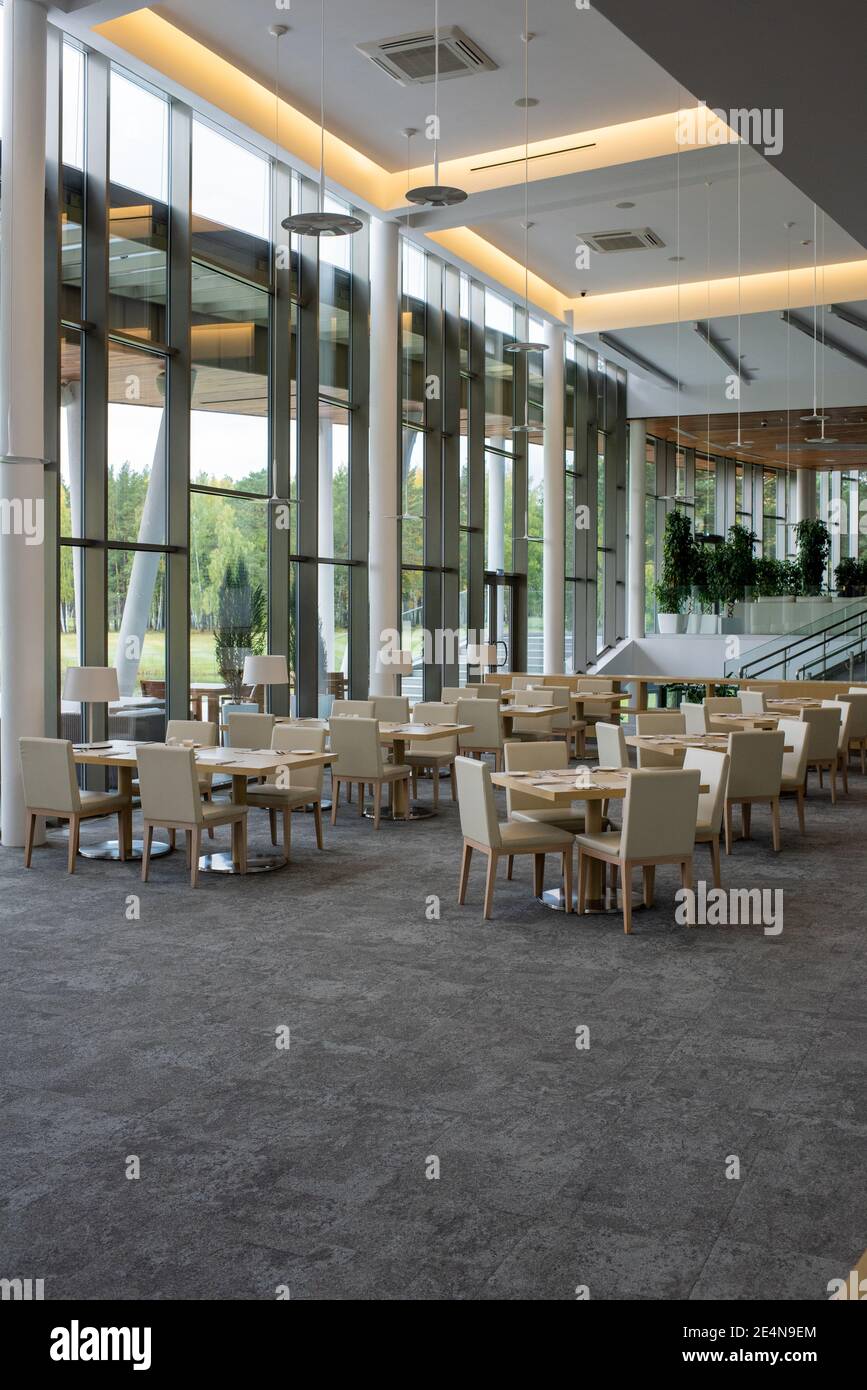 Einrichtung eines 5-Sterne-Restaurants im modernen Business-Center mit Viele Tische umgeben von Stühlen, die an großen Fenstern stehen Stockfoto