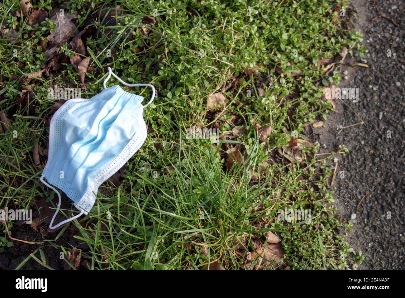 Gebrauchte medizinische Gesichtsmaske außer der Straße entsorgen. Abfall während der COVID-19-Pandemie Stockfoto