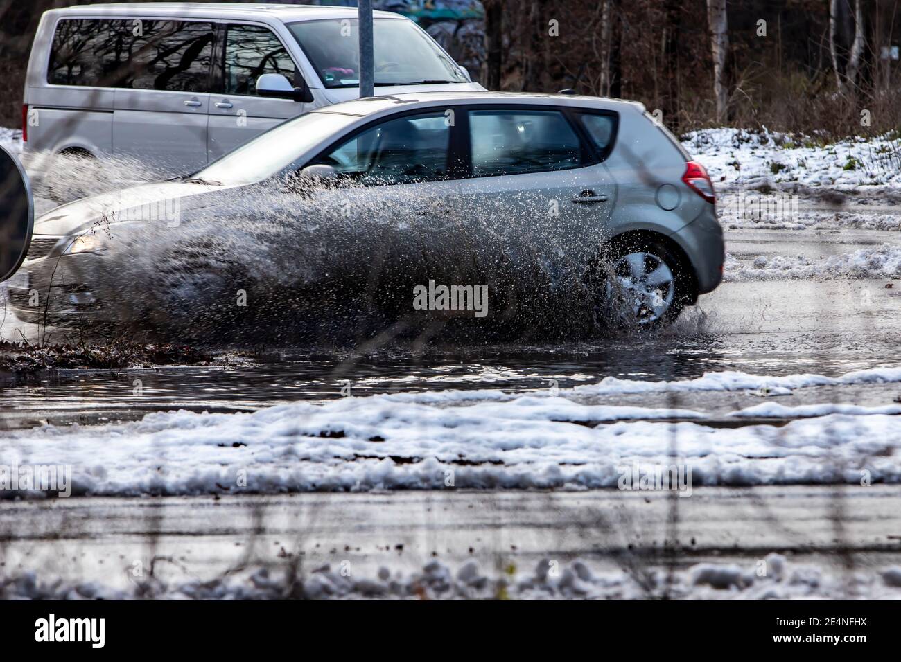 Huerth, NRW, Deutschland, 01 24 2021, ein Auto fährt durch eine Pfütze und das Wasser spritzt auf, Schnee, der langsam auftaut Stockfoto