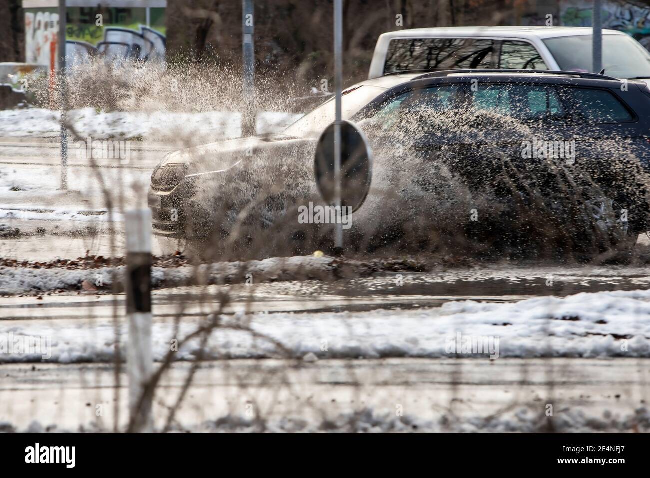 Huerth, NRW, Deutschland, 01 24 2021, ein Auto fährt durch eine Pfütze und das Wasser spritzt auf, Schnee, der langsam auftaut Stockfoto