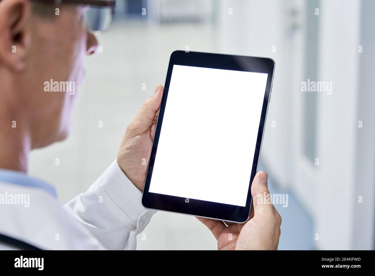 Männliche Arzt hält digitale Tablette mit weißen Mockup-Bildschirm-Technologie. Stockfoto