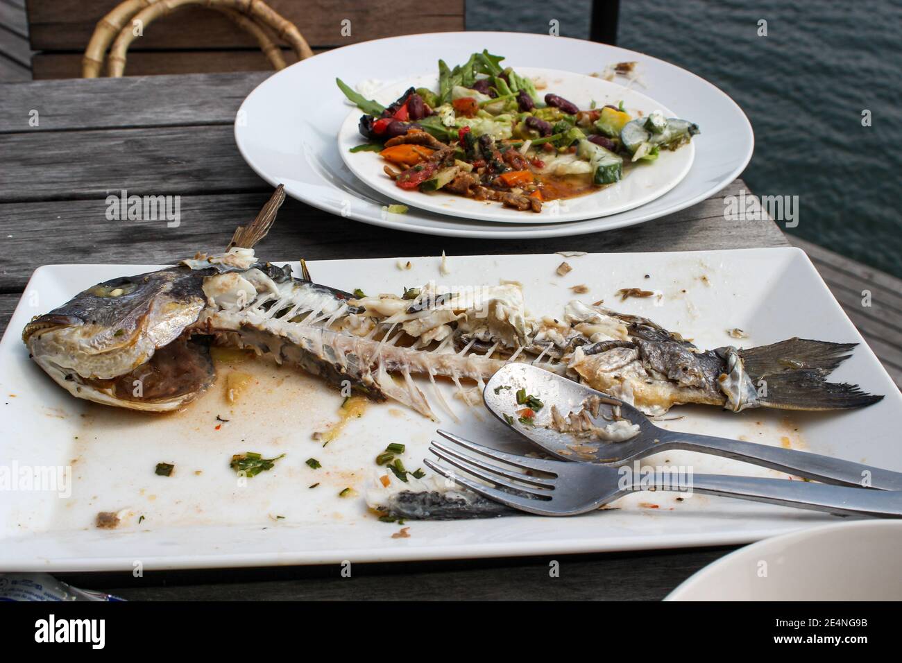 Fertige Teller mit Fischgericht auf Seaside Restaurant Outdoor-Tisch Stockfoto