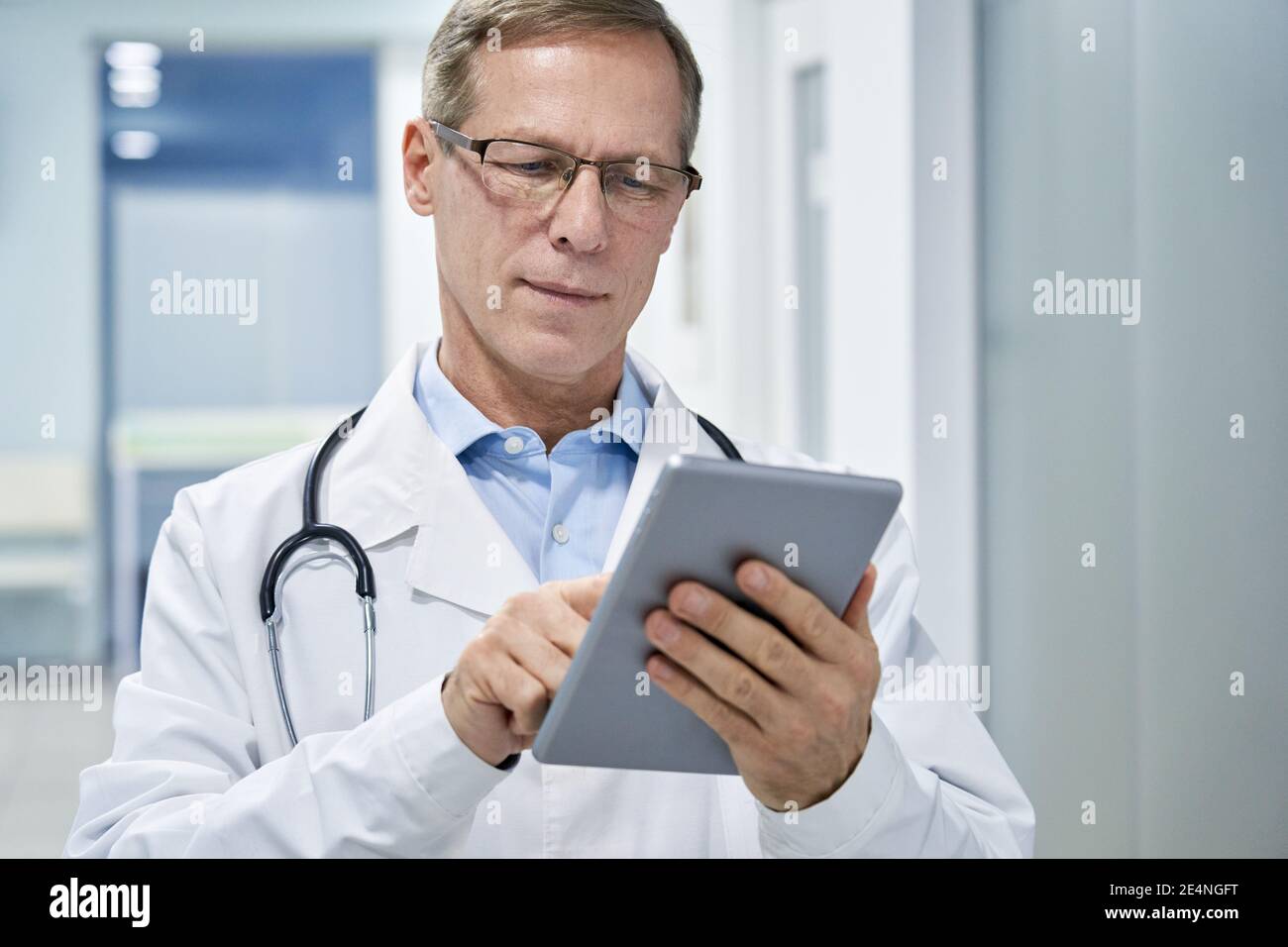 Alter Arzt mit digitalen Tablet e Gesundheit Apps in der Krankenhausberatung online. Stockfoto