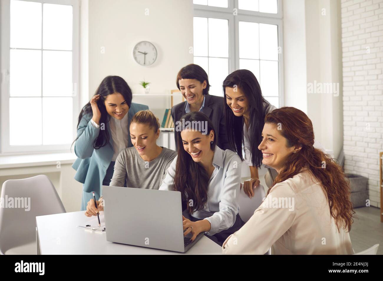 Team von glücklichen jungen Frauen mit Laptop während der Arbeit an Geschäftsprojekt zusammen Stockfoto