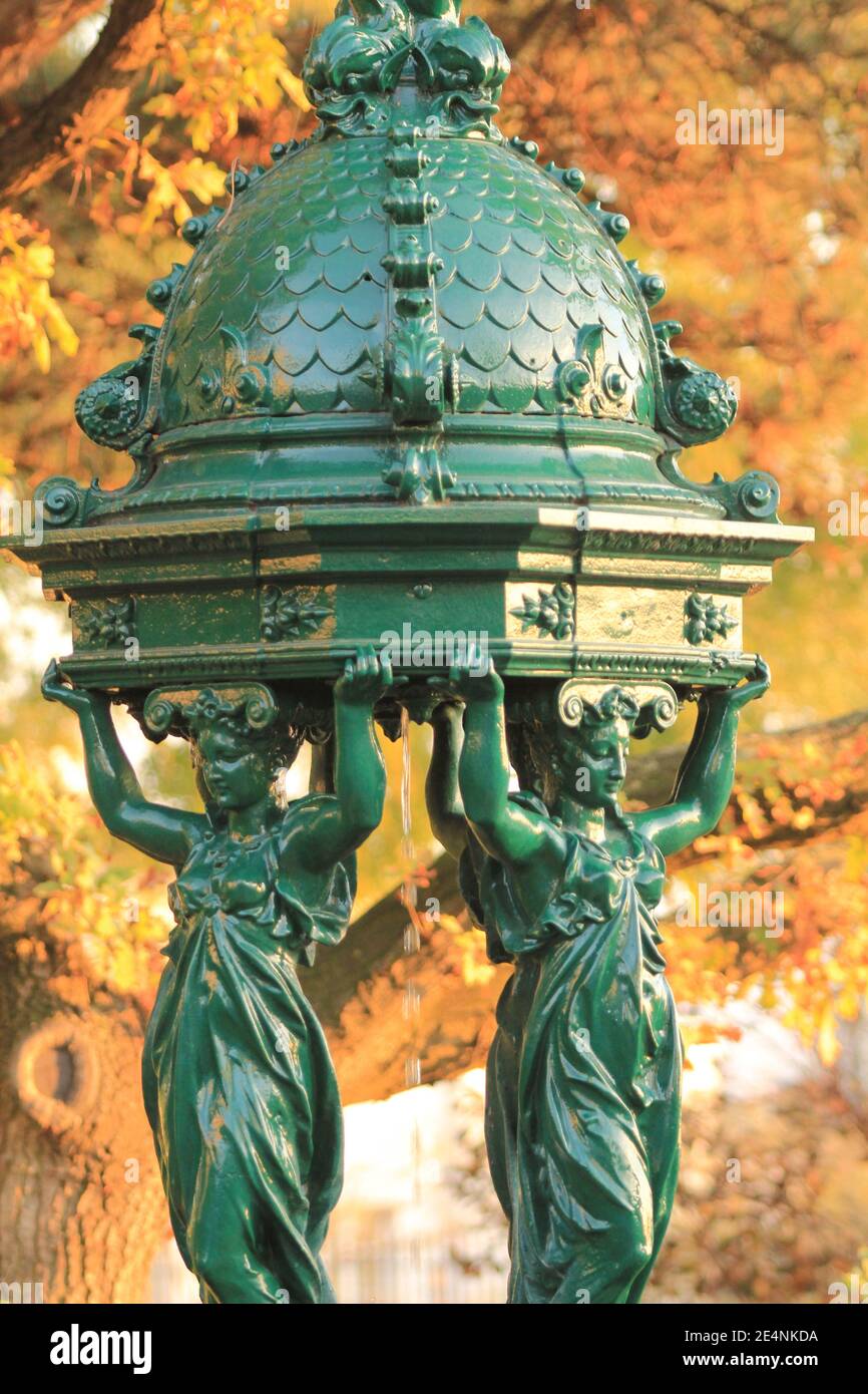 Wallace Brunnen in Paris im Herbst / einer der Trinkbrunnen in Paris im Herbst sogenannte Wallace Fontänen Mit gelbem Laub als Hintergrund Stockfoto