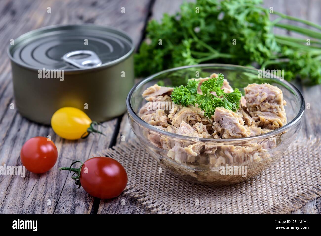 Portion Thunfischsalat mit frischer Petersilie und Kirschtomate auf rustikalem Holztisch. Selektiver Fokus. Stockfoto