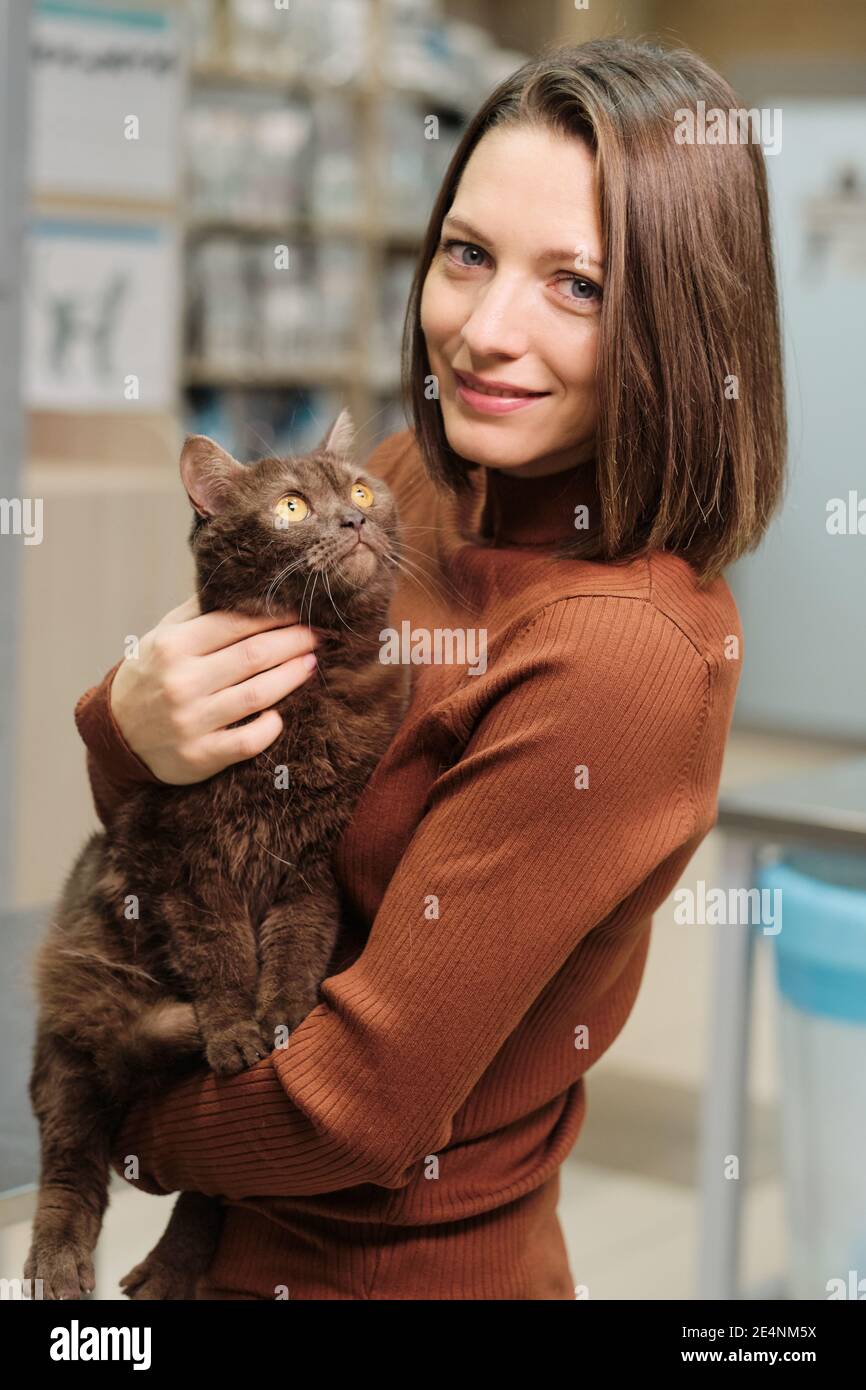 Porträt einer jungen Frau, die die Kamera anschaut und sie hält Wunderschöne Katze Stockfoto