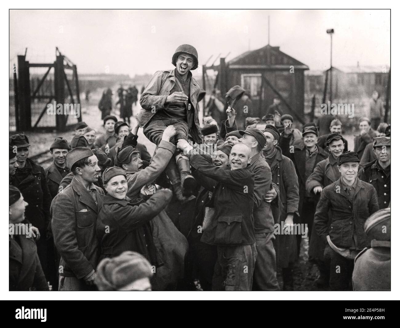 ESELHEIDE-BEFREIUNG WW2 Nazi-Konzentrationslager Befreiung Russische Kriegsgefangene, die einen amerikanischen Soldaten nach der Befreiung der US-Armee 9th aus ihrem Lager in Eselheide, Deutschland, aufhoben 9th. April 1945 Stockfoto
