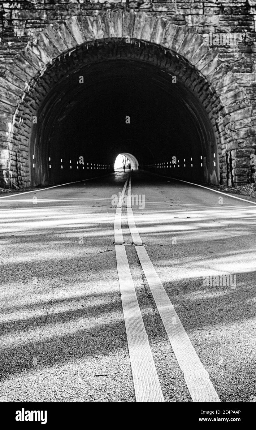Straßenlinien führen in einen kreisförmigen Tunnel auf dem Blue Ridge Parkway in der Nähe von Asheville, NC, USA Stockfoto