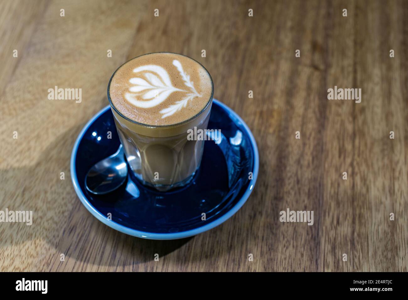 Glas eines flachen weißen Kaffees auf rustikalem Holztisch Nahaufnahme. Stockfoto