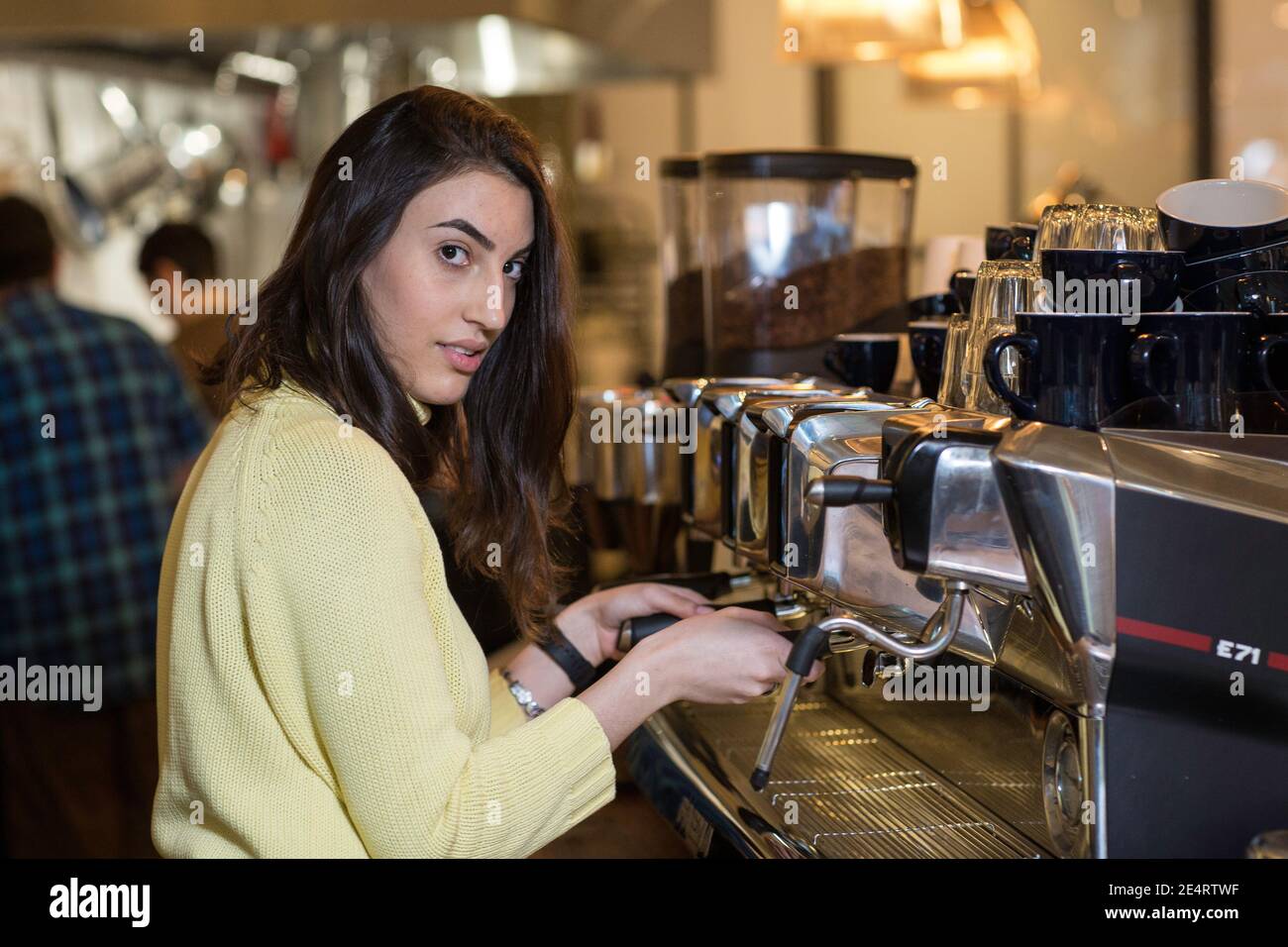 Coffee Business Concept - Portrait einer Barista, die im Café Kaffee mit Espressomaschine zubereitet. Stockfoto
