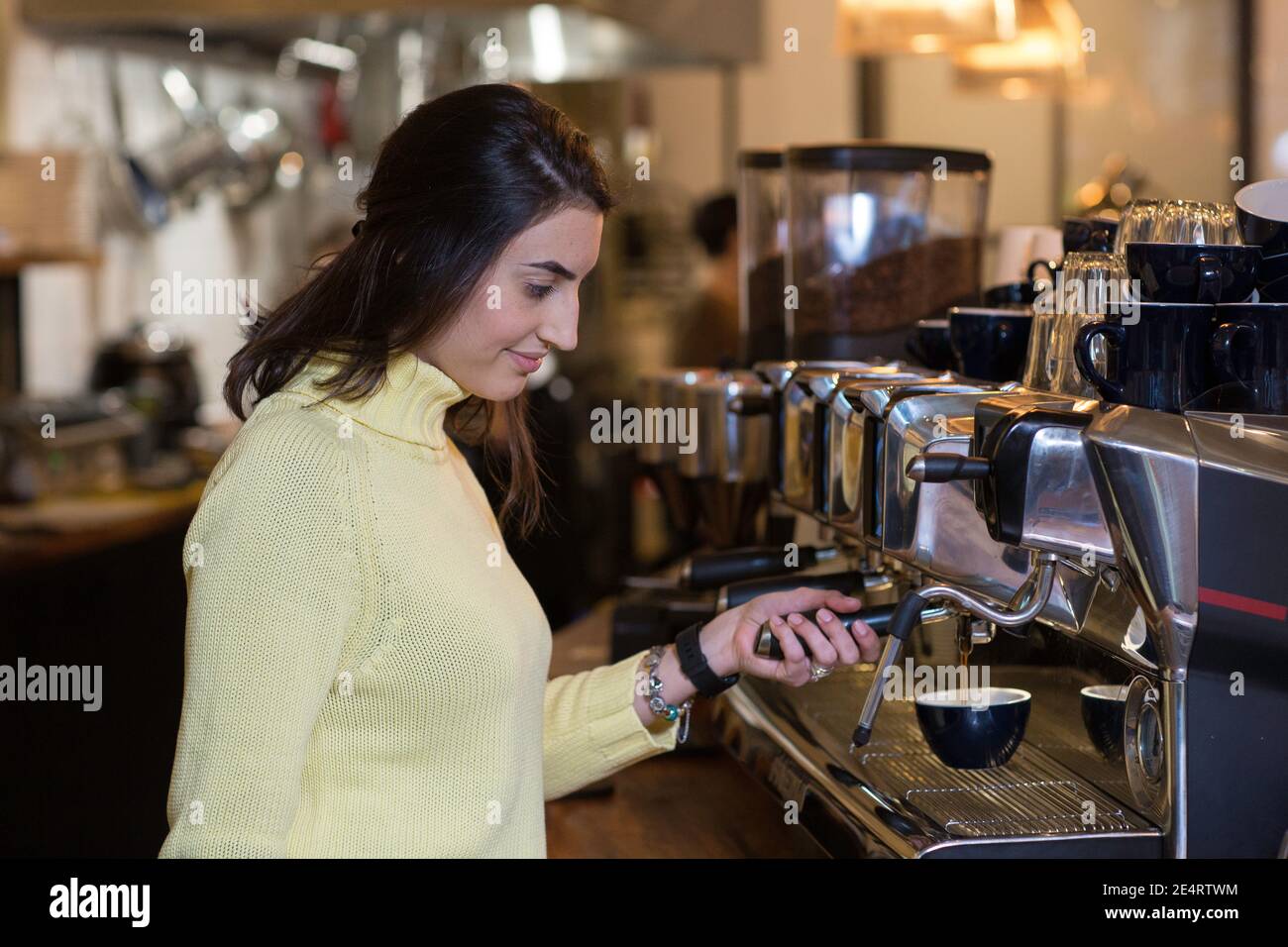 Coffee Business Concept - Portrait einer Barista, die im Café Kaffee mit Espressomaschine zubereitet. Stockfoto