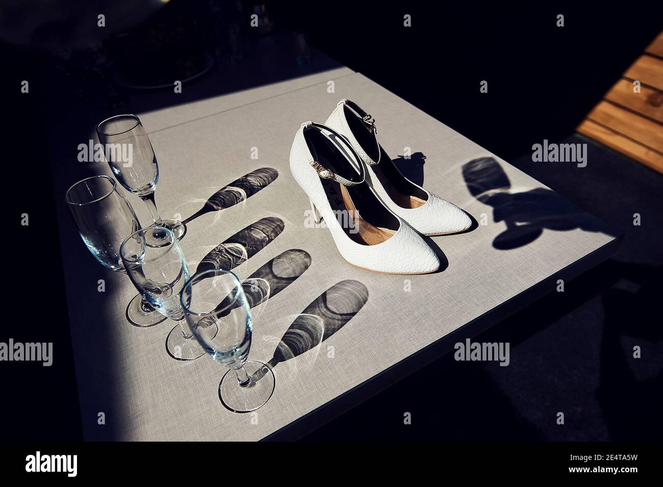 Weiße Braut Schuhe und Gläser in der Nähe. Weiße Braut Schuhe und Gläser in der Nähe. Stockfoto