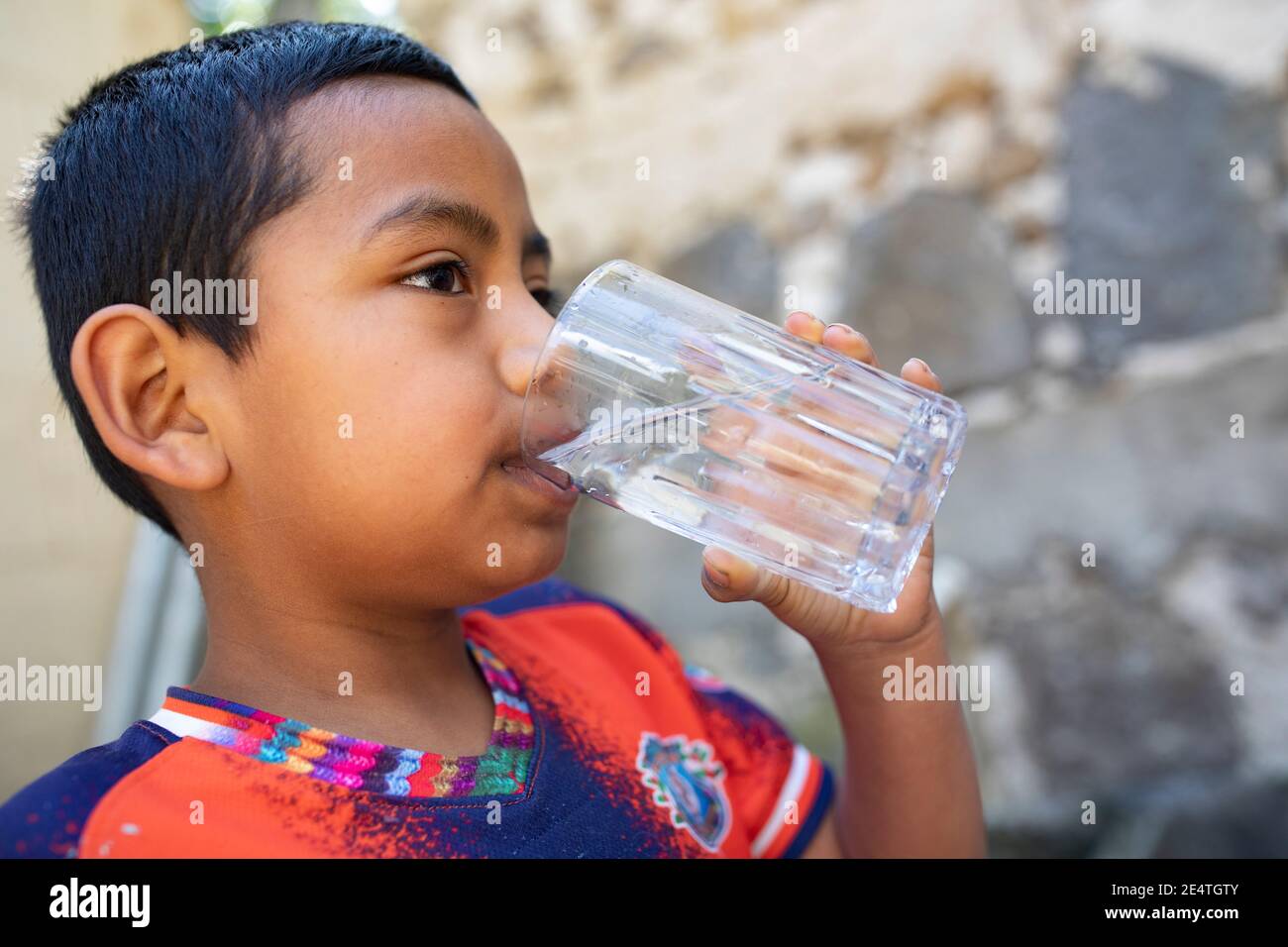 Ein Kind trinkt ein Glas sauberes Wasser in San Juan la Laguna, Guatemala. Stockfoto