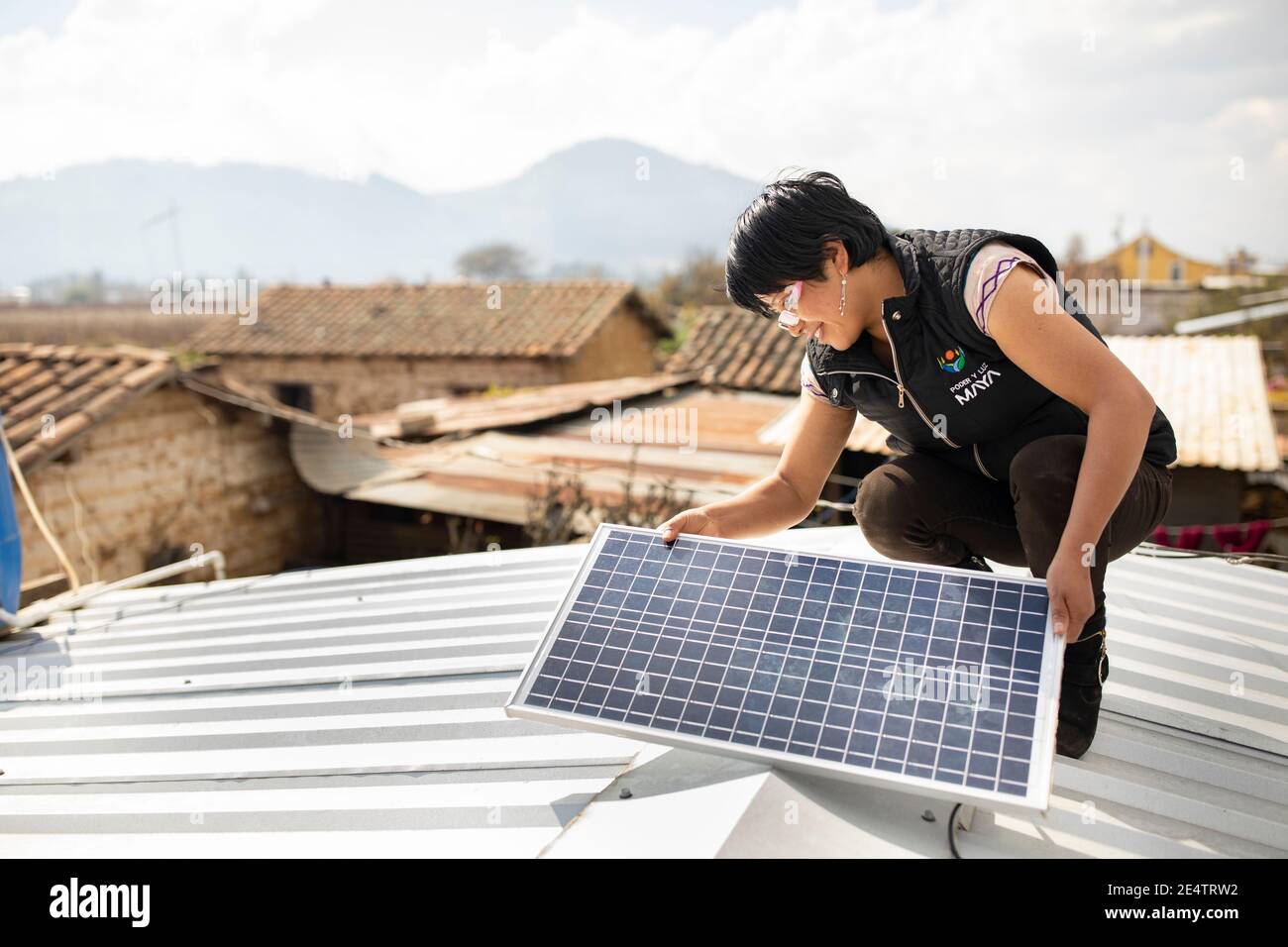 Ein Techniker von einem lokalen gemeinnützigen Energieversorger installiert ein neues solarbetriebenes Beleuchtungssystem auf einem Haus in Cantel, Guatemala. Stockfoto