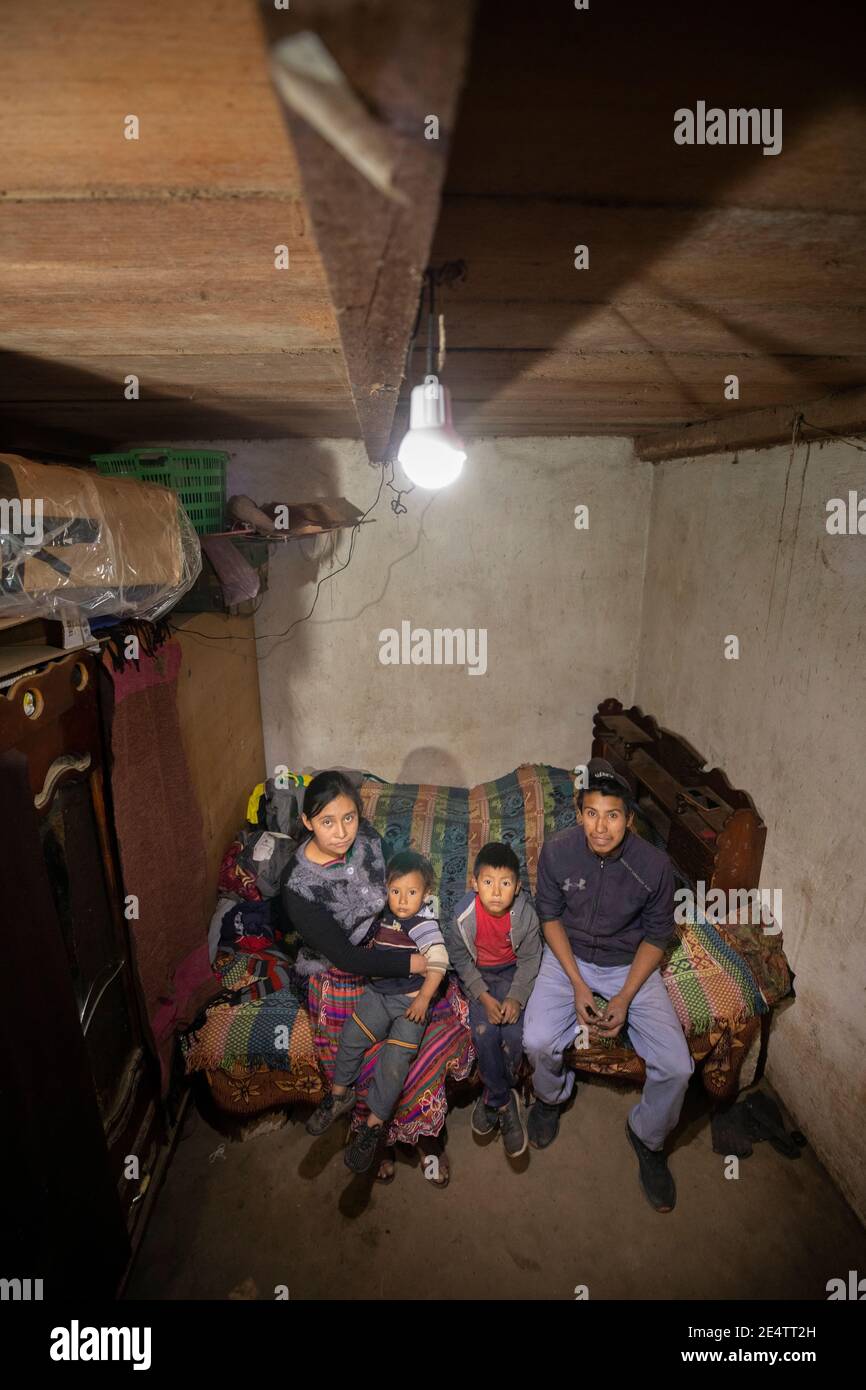 Familie, die ein neues solarbetriebenes Beleuchtungssystem in ihrem Zuhause in Cantel, Guatemala, Mittelamerika, verwendet. Stockfoto