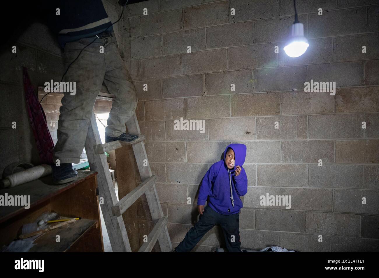 Kinder unter einer beleuchteten Glühbirne in ihrem Zuhause Cantel, Guatemala, Mittelamerika. Stockfoto