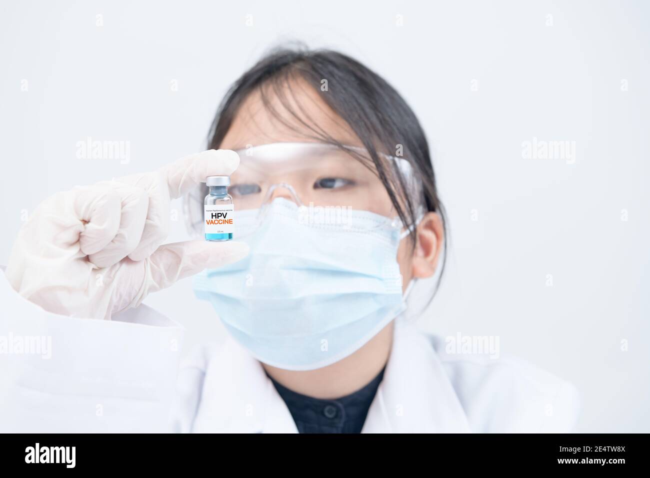Kleiner Wissenschaftler oder Arzt, der HPV-Impfstoff auf weißem Hintergrund hält. Impfstoff schützt vor Meningitis und Keuchhusten. Stockfoto
