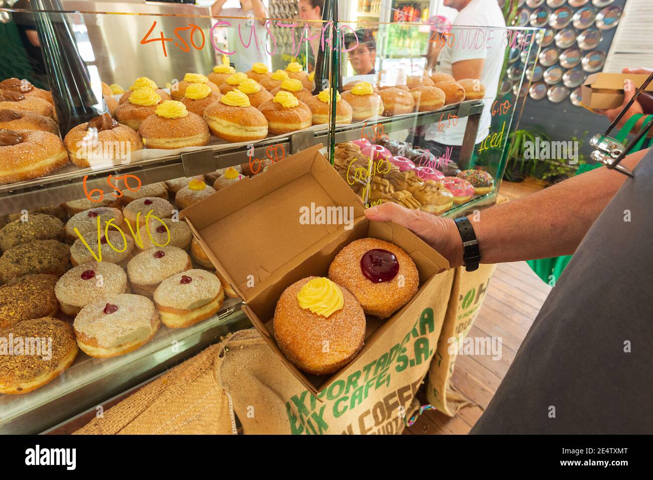 Person, die eine Kiste mit Donuts in der Kenilworth Country Bakery, South East Queensland, QLD, Australien hält Stockfoto