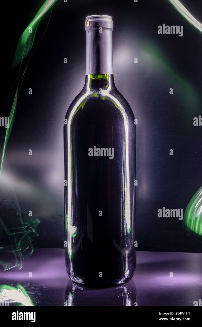 Schwarze Flasche Wein auf schwarzem Hintergrund mit Licht Schienen und Reflexionen Stockfoto