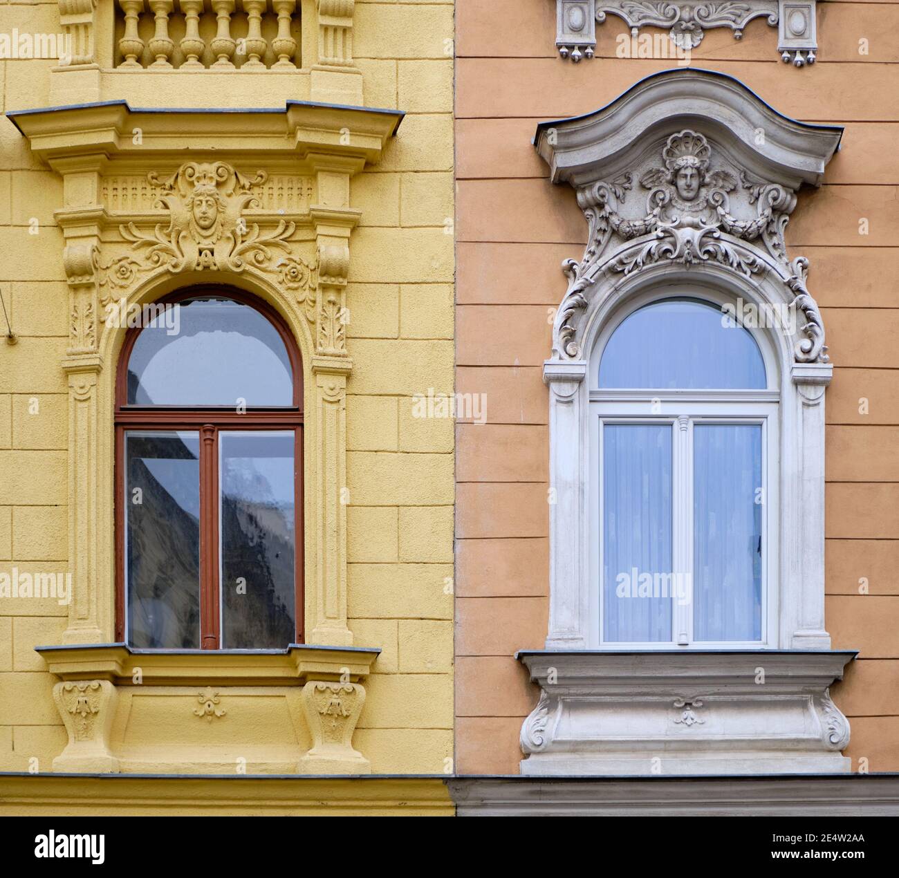 Fenster von zwei angrenzenden Gebäuden mit unterschiedlicher Architektur und Farben In Wien Stockfoto