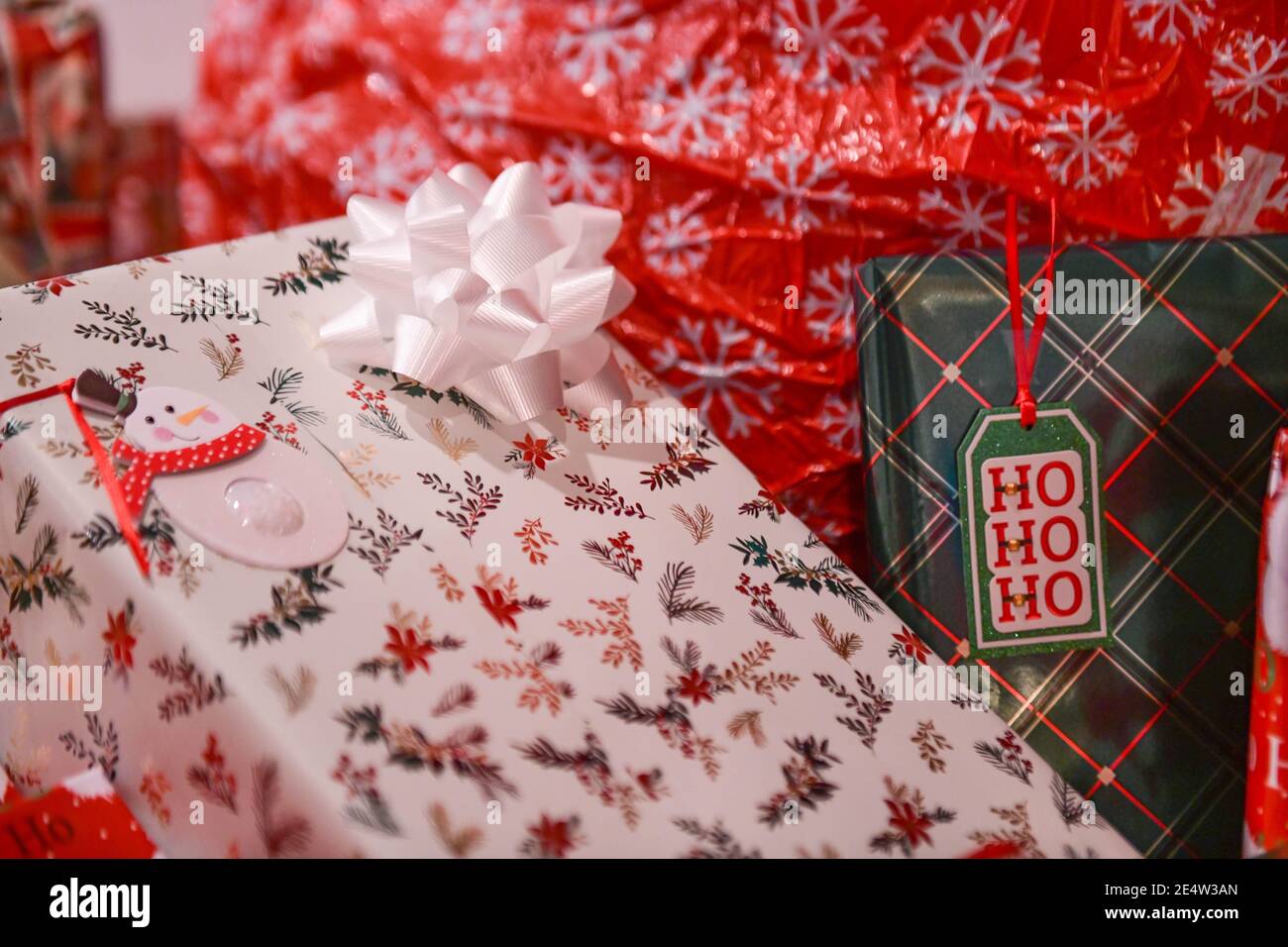 Weihnachtsgeschenke mit Geschenkanhänger - Weihnachtsstapel - verpackt Geschenke - Geschenk mit Geschenkanhänger unter einem Weihnachtsbaum - Weihnachtsschmuck und Bögen Stockfoto