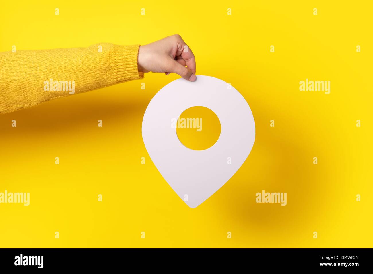Weißer Kartenzeiger 3d-Pin. Standortsymbol in der Hand auf gelbem Hintergrund Stockfoto