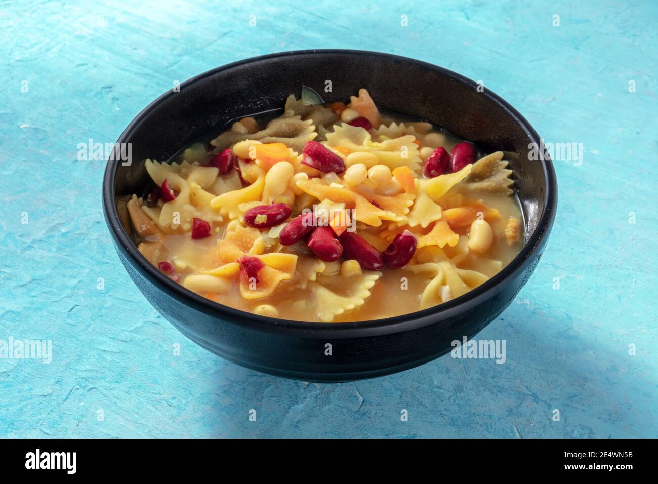 Vegane Suppe mit Gemüse, Nudeln und Bohnen, auf blauem Hintergrund Stockfoto