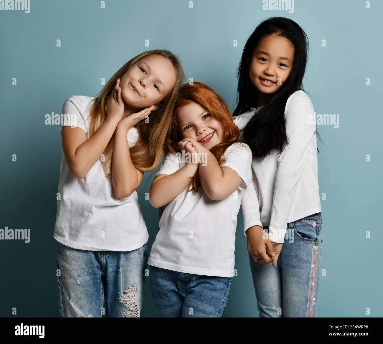 Internationale Kinder Mädchen Freunde in Jeans und weißen T-Shirts stehen Zusammen schmelzendes Gefühl berührte Liebe Stockfoto