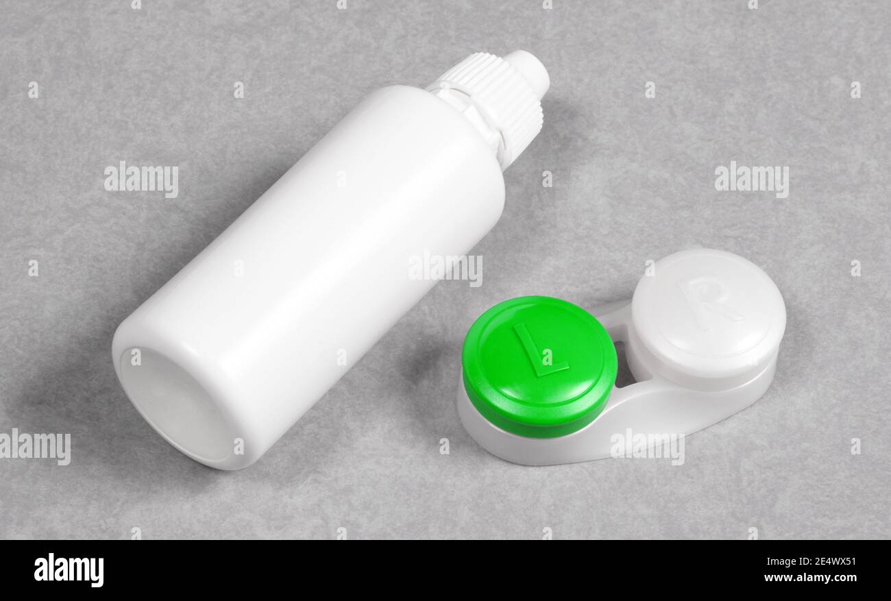 Grünes Kontaktlinsengehäuse und Flasche mit Lösung, isoliert auf grauem Hintergrund Stockfoto