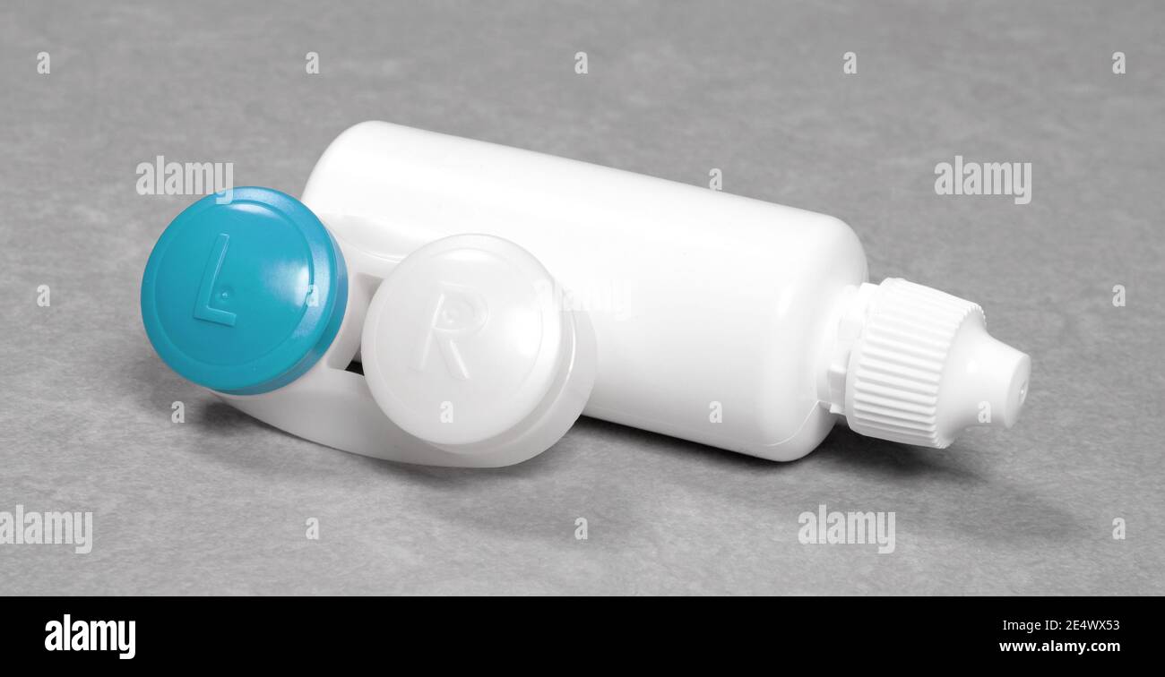 Blauer Kontaktlinsenkoffer und Flasche mit Lösung, isoliert auf grauem Hintergrund Stockfoto
