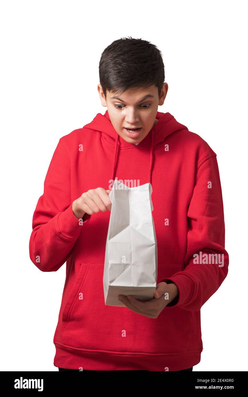 Überrascht überglücklich Teenager Jungen Öffnung weißen Papiertüte Blick in Paket mit Gesichtsausdruck Stockfoto