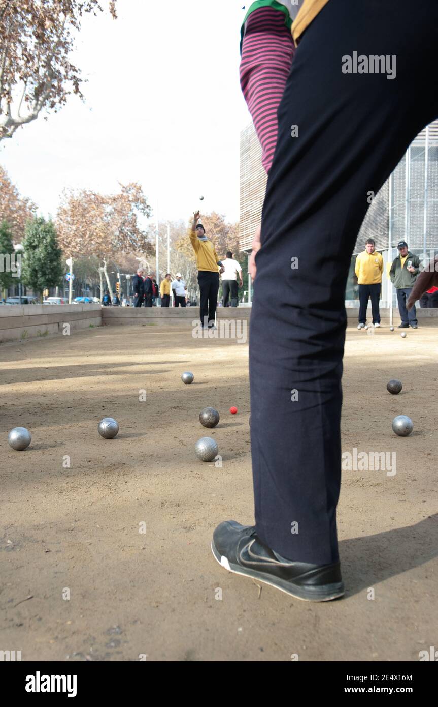 Barcelona, Spanien - 11. Dezember 2011: Männer spielen Bocce: Der Spieler wirft den Ball in die Luft schwingenden Arm; Fokus ist auf dem 'Bube' auch als A Stockfoto