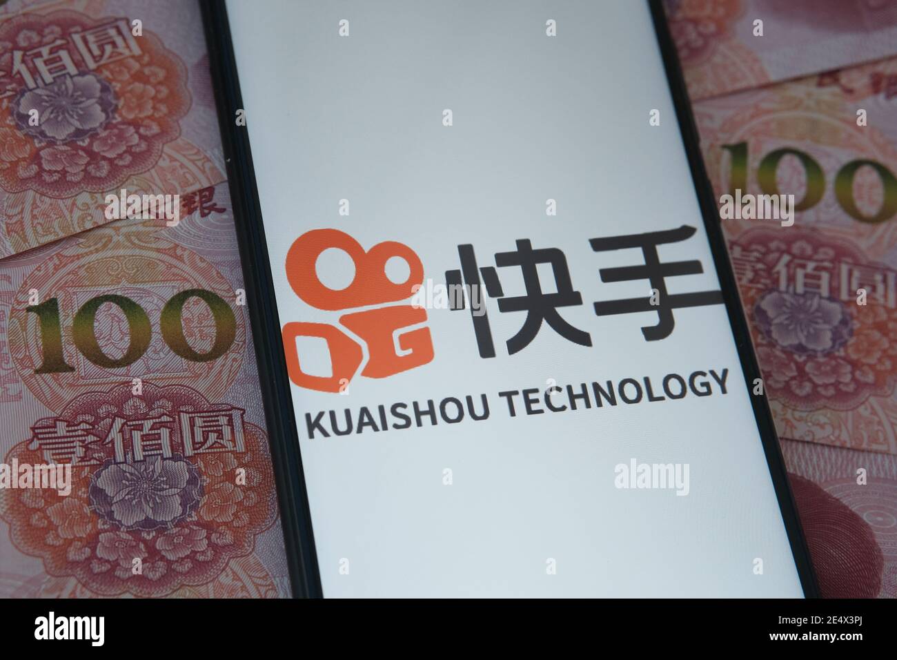 Stafford, Großbritannien - Januar 25 2021: Kuaishou App-Logo auf dem Smartphone-Bildschirm und verschwommene chinesische Yuan-Banknoten auf dem Hintergrund. Konz Stockfoto