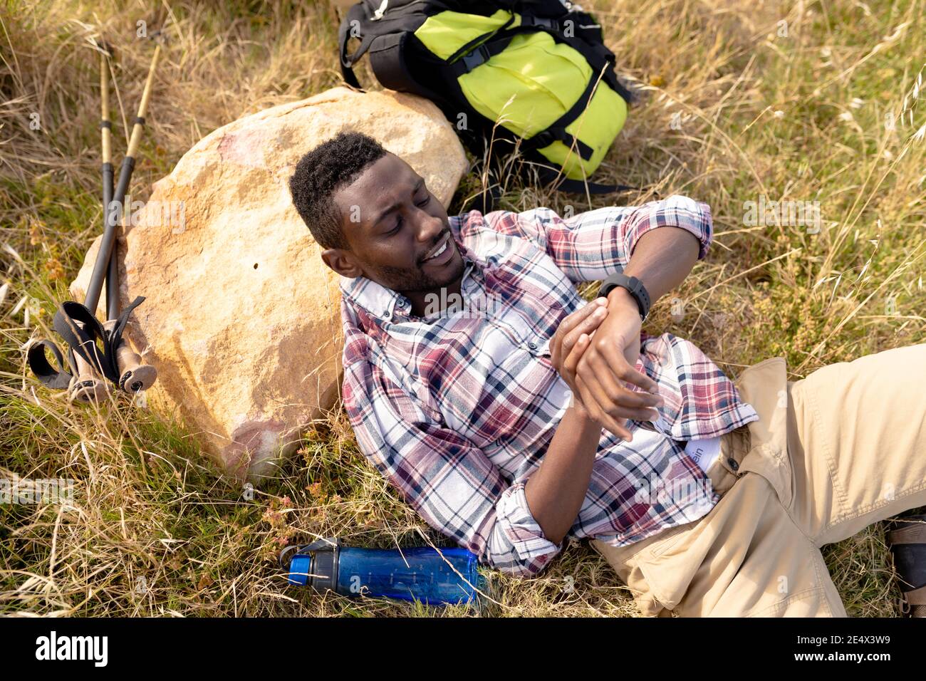 Fit afroamerikanischen Mann ruht Überprüfung Smartwatch und liegend in Berglandschaft Stockfoto