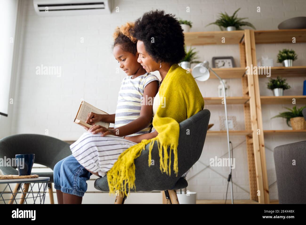 Kleines Mädchen, das Buch mit Mutter zu Hause liest Stockfoto