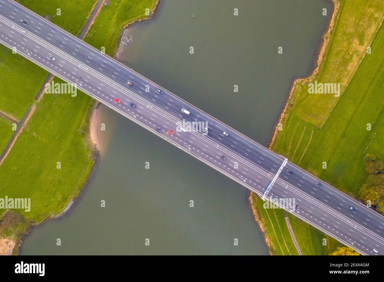 Luftaufnahme von oben nach unten von riesigen Flachland Fluss IJssel mit Autobahnbrücke durch landwirtschaftliche Landschaft. Zwolle, Overijssel Provinz, Niederlande. Dr Stockfoto