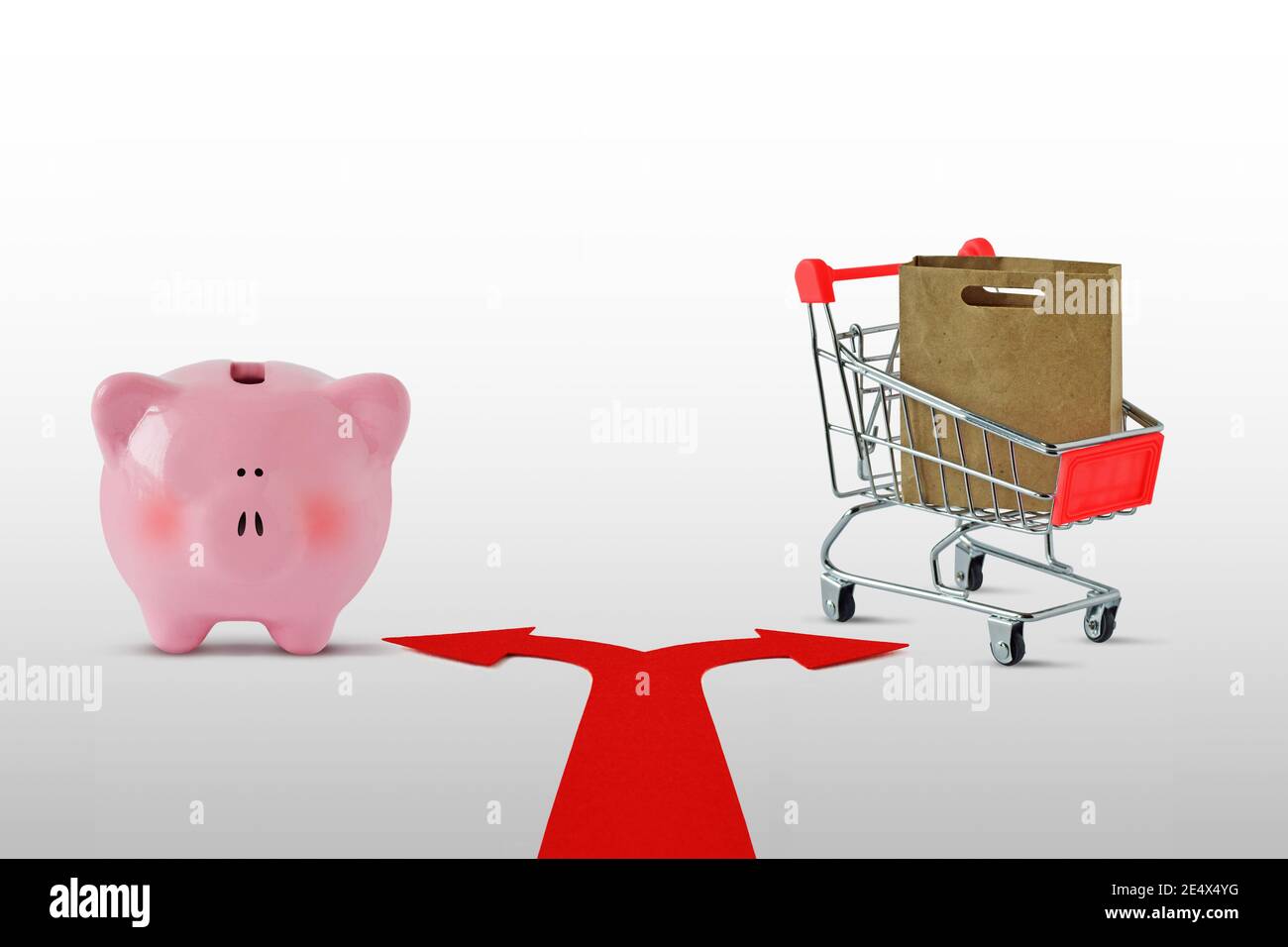 Zwei-Wege-Pfeile mit Sparschwein und Warenkorb - Konzept der Wahl zwischen Sparen und Einkaufen Stockfoto
