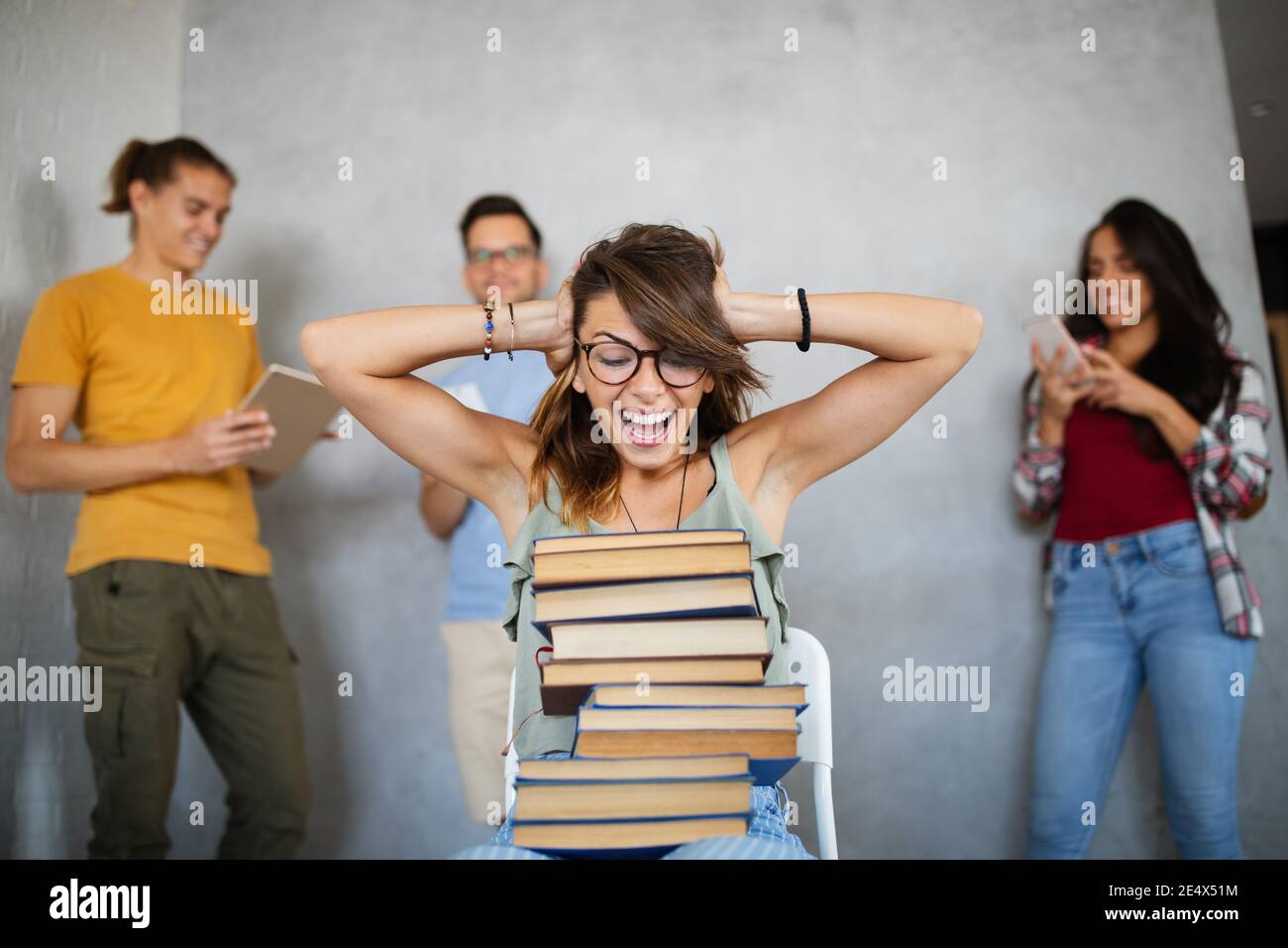 Unglücklich Student Mädchen Blick auf ihre faulen Kumpels, die sind Spielen mit dem Telefon statt zu arbeiten Stockfoto